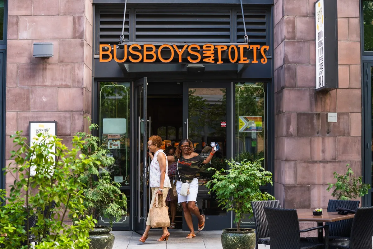 Guests outside the Busboys and Poets entrance beneath its sign